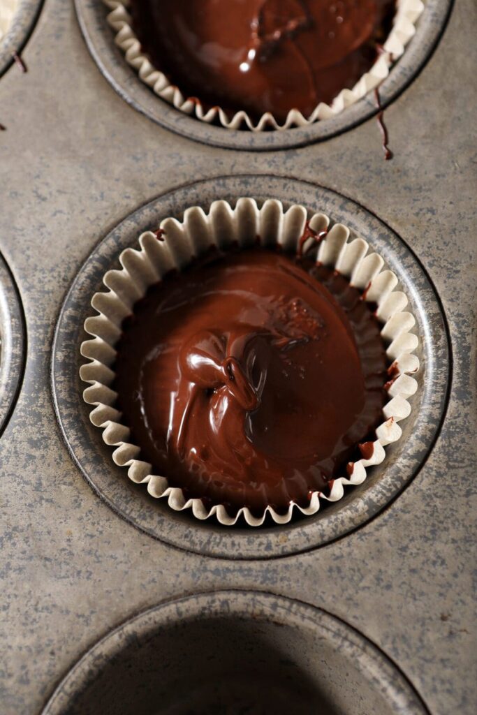 Warm chocolate on top of peanut butter in a muffin tin to make homemade peanut butter cups