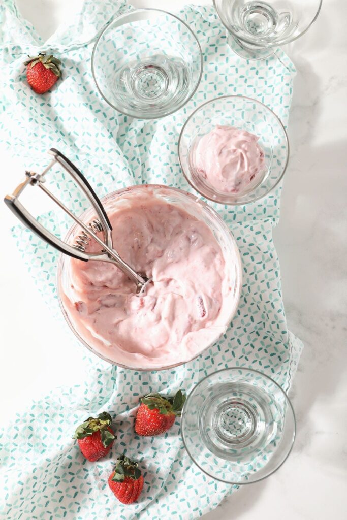 A scoop sits in a bowl of strawberry pudding before it's dolloped into glasses