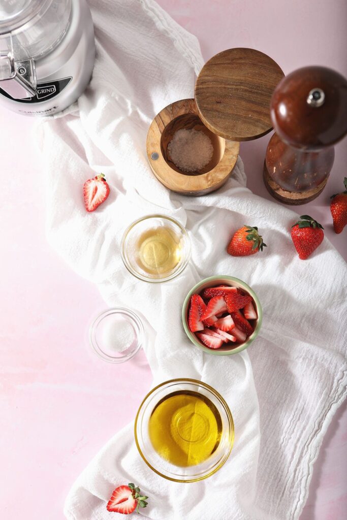 Ingredients for homemade salad dressing on a white cloth on top of a pink surface