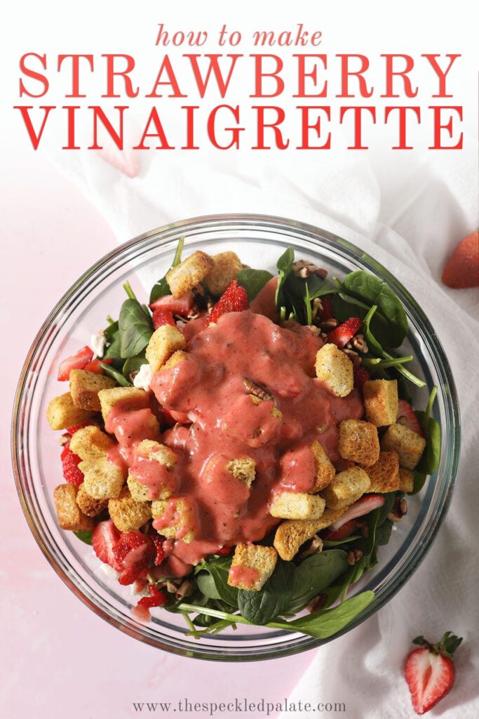 Strawberry salad dressing on top of a spinach salad in a bowl before tossing on a pink surface with the text 'how to make strawberry vinaigrette'