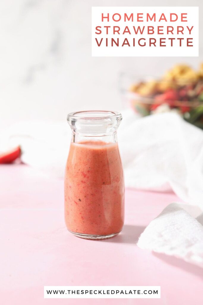 A bottle of strawberry vinaigrette sits in front of a salad bowl with the text 'homemade strawberry vinaigrette'