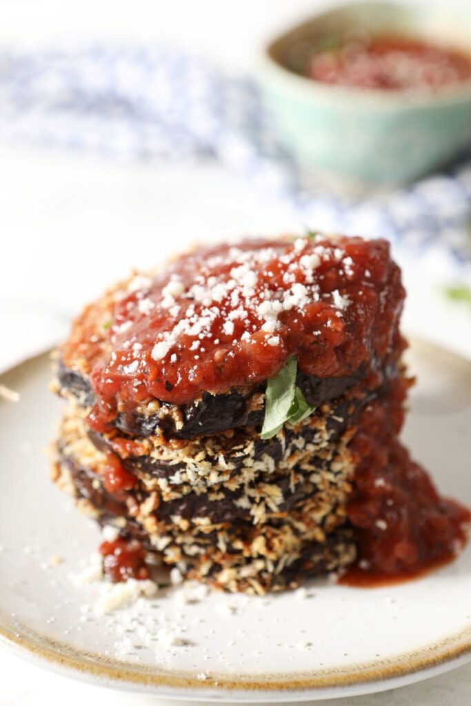 A stack of sliced Crispy Baked Eggplant Slices on a white plate