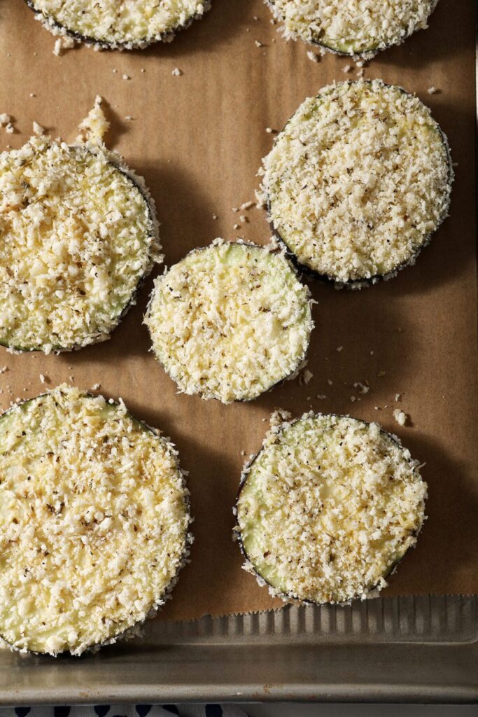 Coated eggplants on a sheet pan before baking