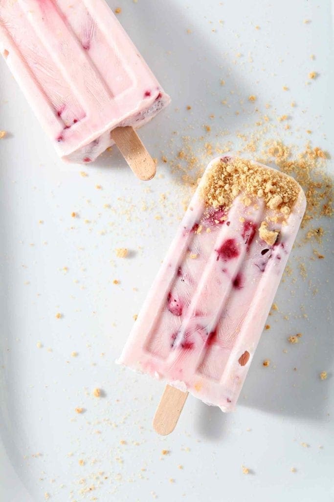 Two Roasted Strawberry Cheesecake Pops sit on a white platter