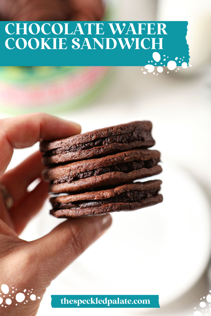 A hand holds three chocolate sandwich cookies with mint chocolate ganache over a plate and a cookie tin with the text chocolate wafer cookie sandwich