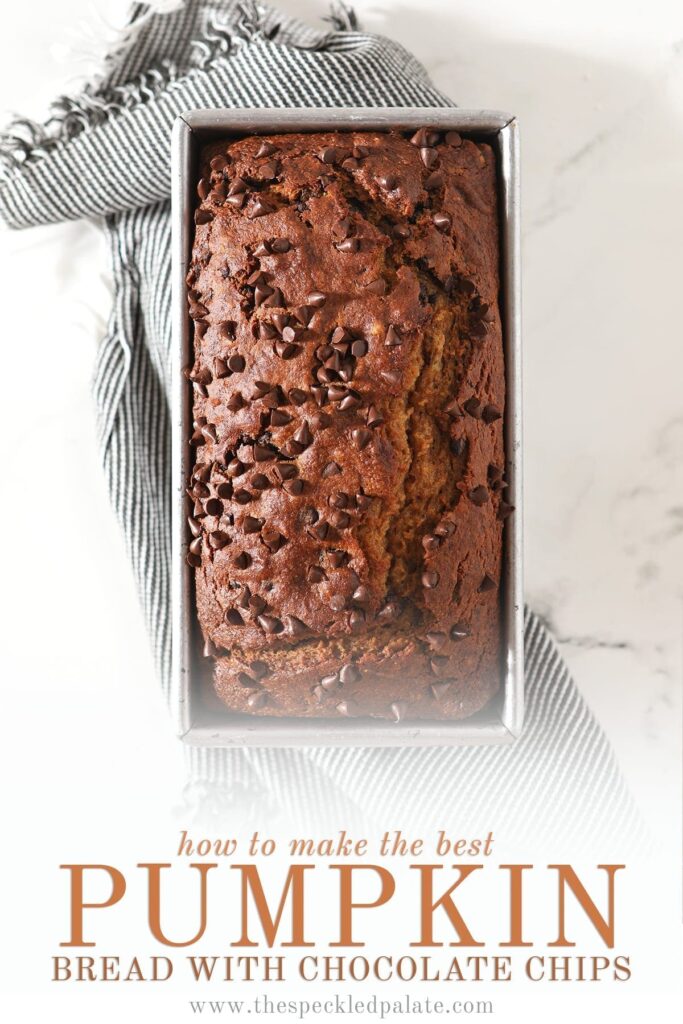 Overhead of a chocolate chip-studded loaf in a metal tin on top of a gray towel with the text 'how to make the best pumpkin bread with chocolate chips'