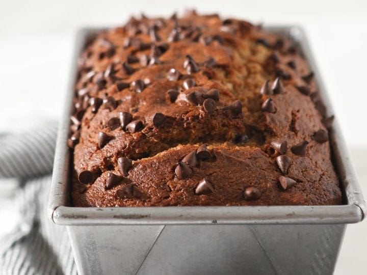 Close up of a loaf of pumpkin bread in a metal pan topped with chocolate chips