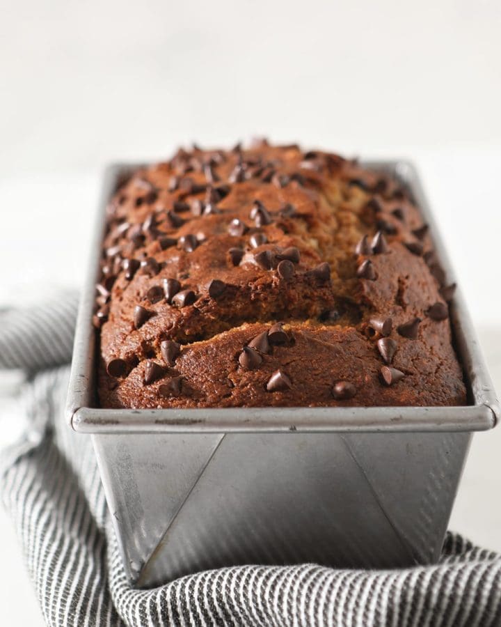 Close up of a loaf of pumpkin bread in a metal pan topped with chocolate chips