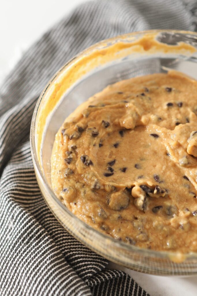 Pumpkin bread batter in a glass bowl on a gray striped towel