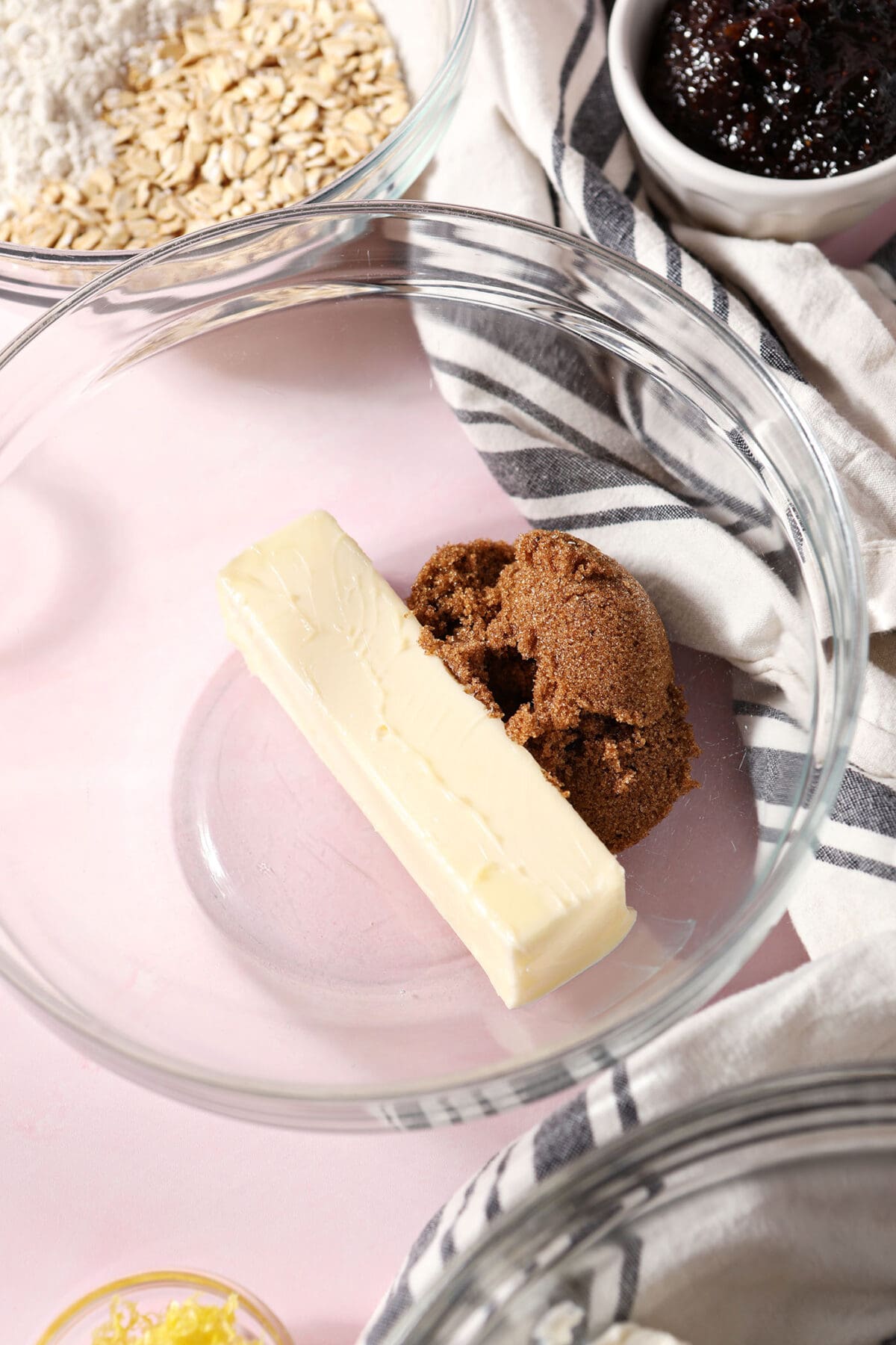 brown sugar and a stick of butter in a bowl on a pink surface