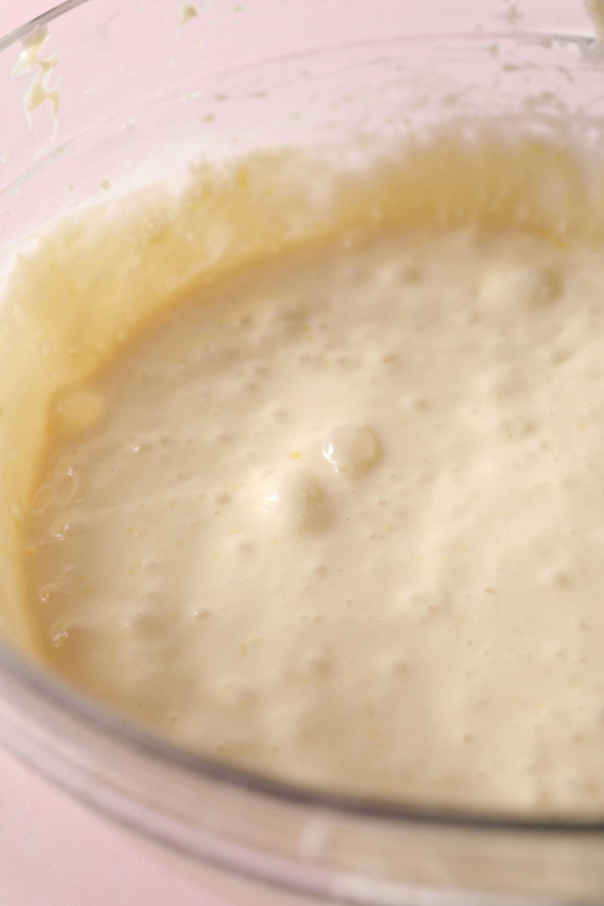 the final lemon cheesecake filling mixture in a bowl on a pink surface