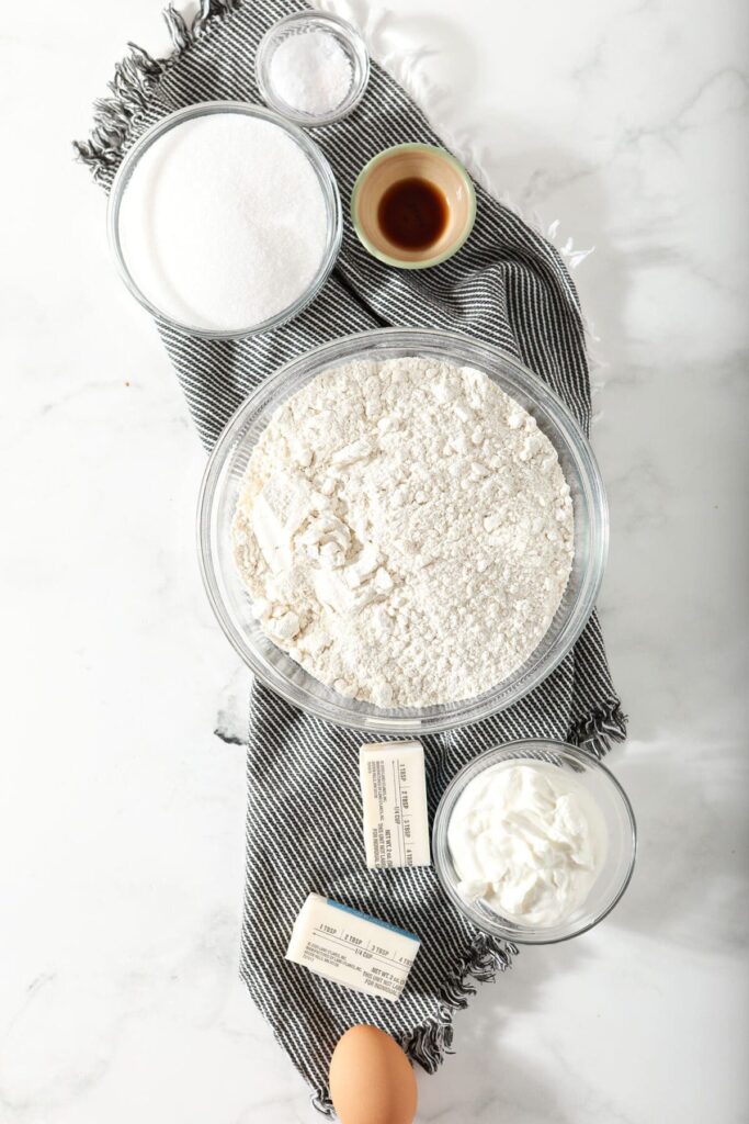 Ingredients to make Greek yogurt cookies in bowls on a marble countertop