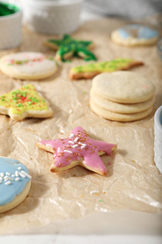 Various shapes of sugar cookies frosted with different colors and sprinkles on parchment