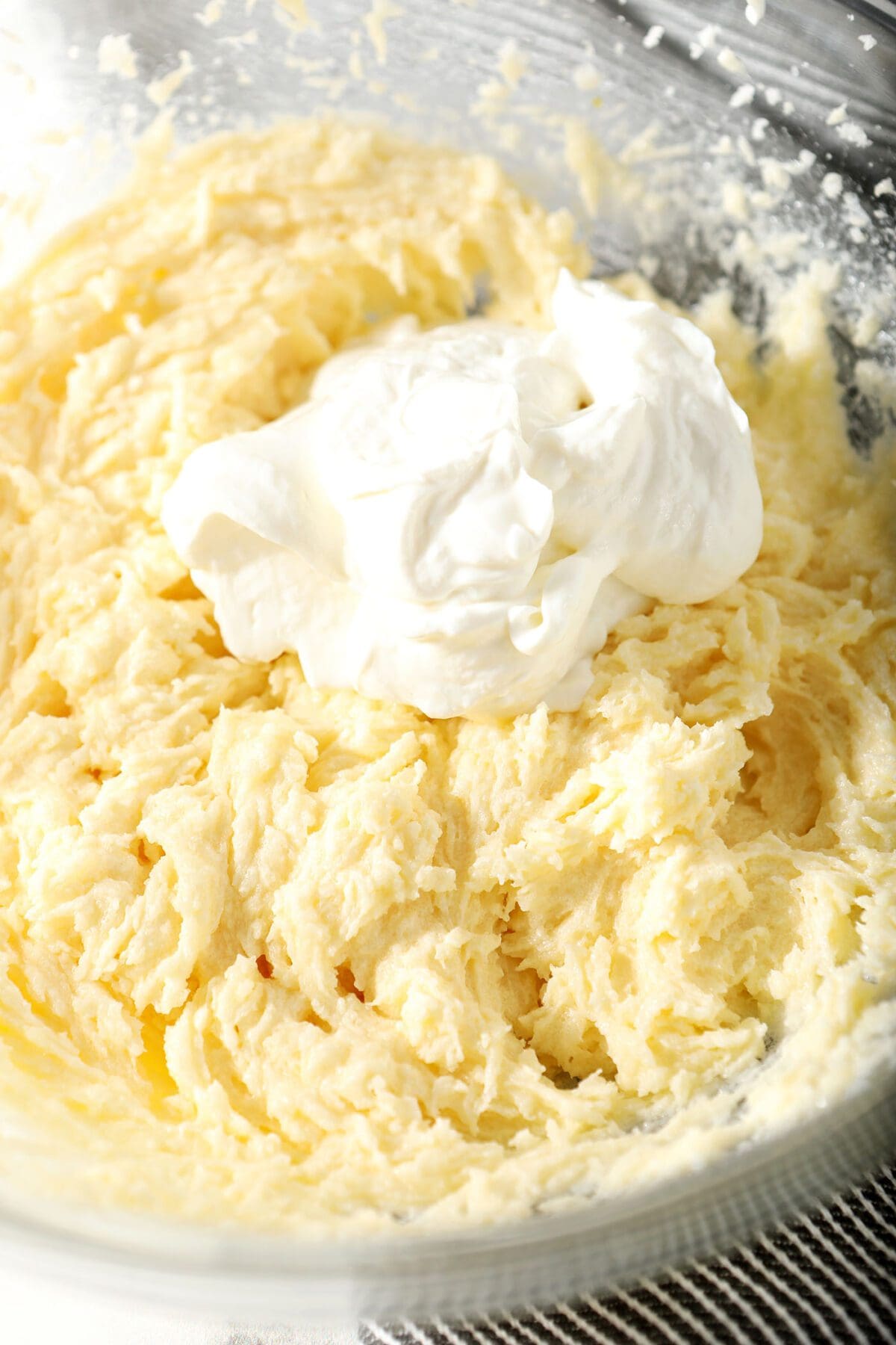 A scoop of Greek yogurt on top of other wet ingredients for the sugar cookies