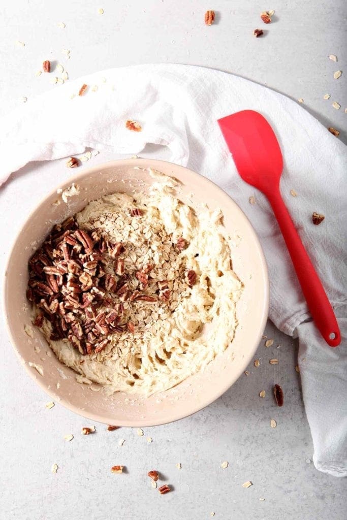 Toasted pecans and oats are sprinkled on top of the Quebec Maple Pecan Drop Cookie batter before being mixed in