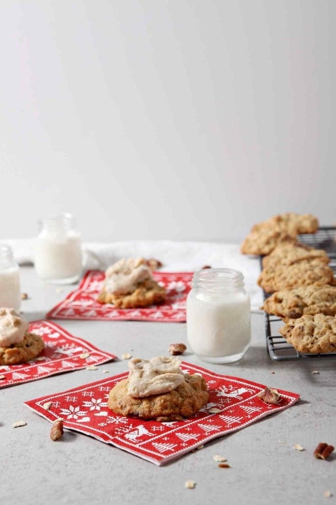 Several iced Quebec Maple Pecan Drop Cookies are served with small mason jars of milk