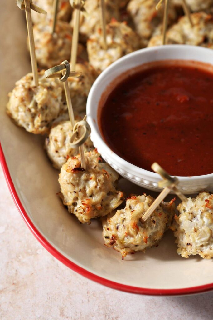 Skewered meatballs on a platter with marinara