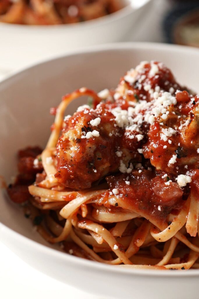 Close up of a bowl of pasta in red sauce with meatballs