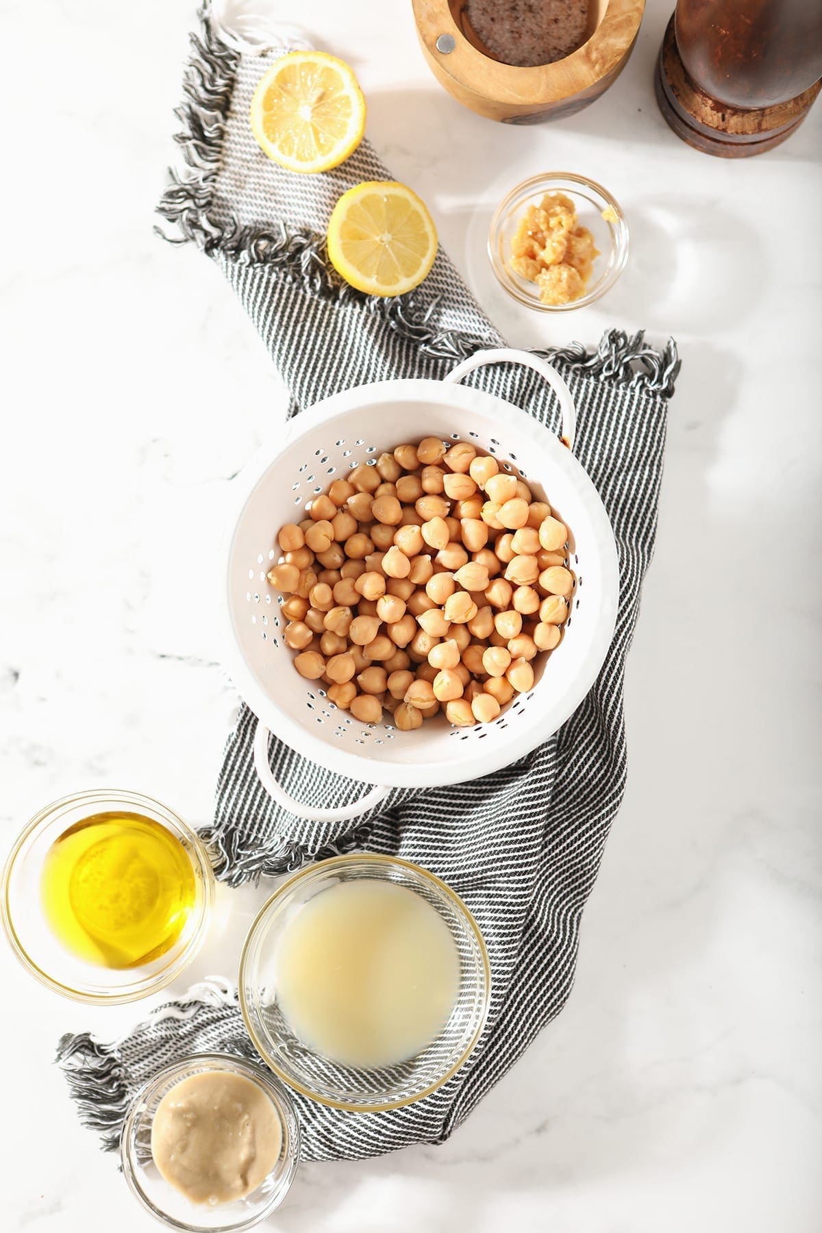 Chickpeas in a colander are surrounded by other ingredients, before the dip is made