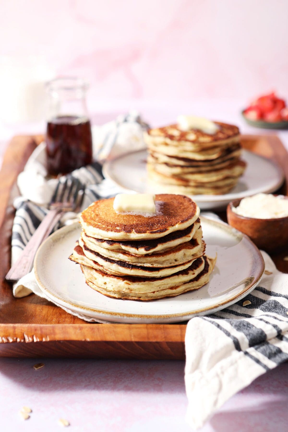 Two plates with stacks of oat flour pancakes on a wooden board for serving