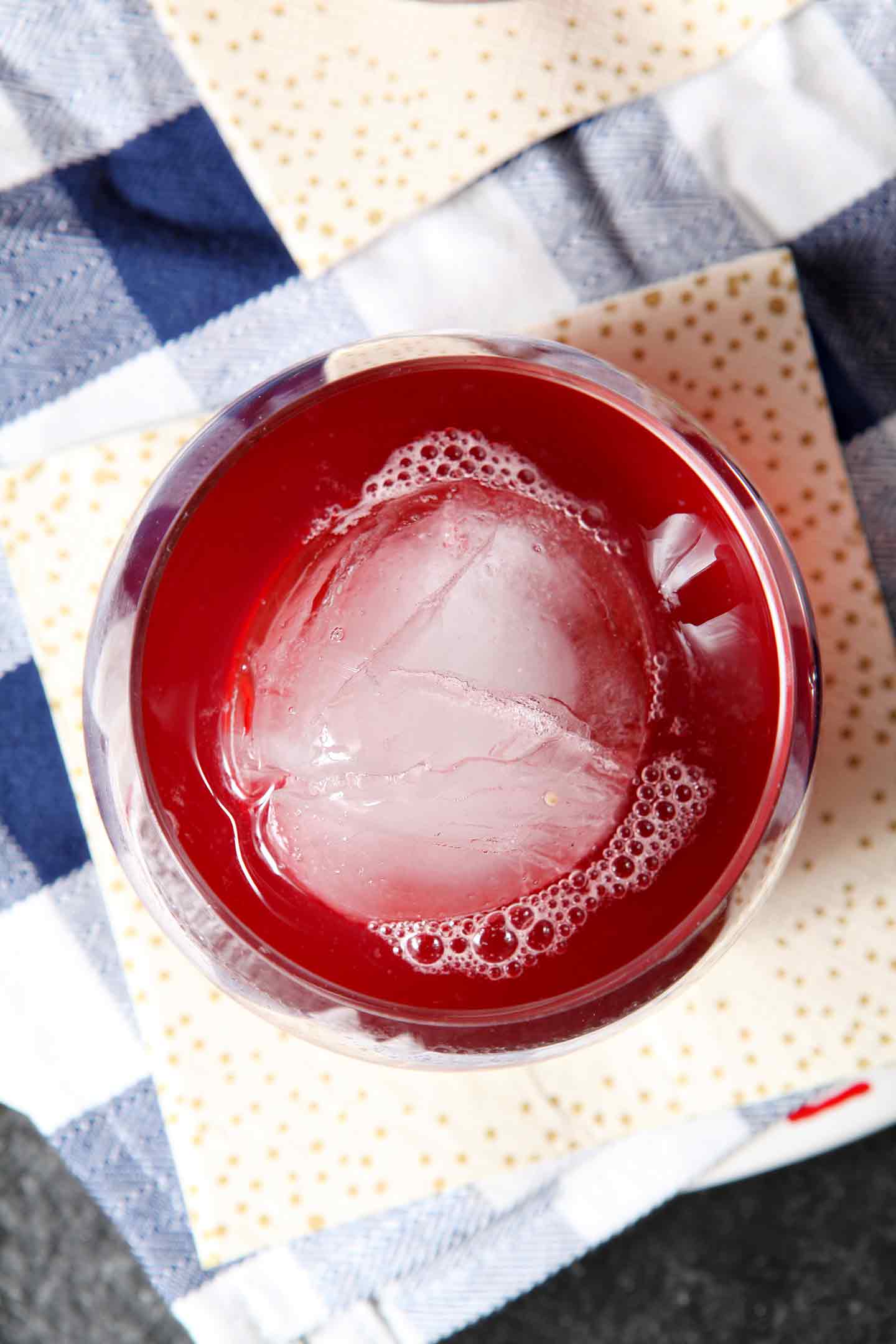 Overhead close up of round ice cube in glass with beverage 