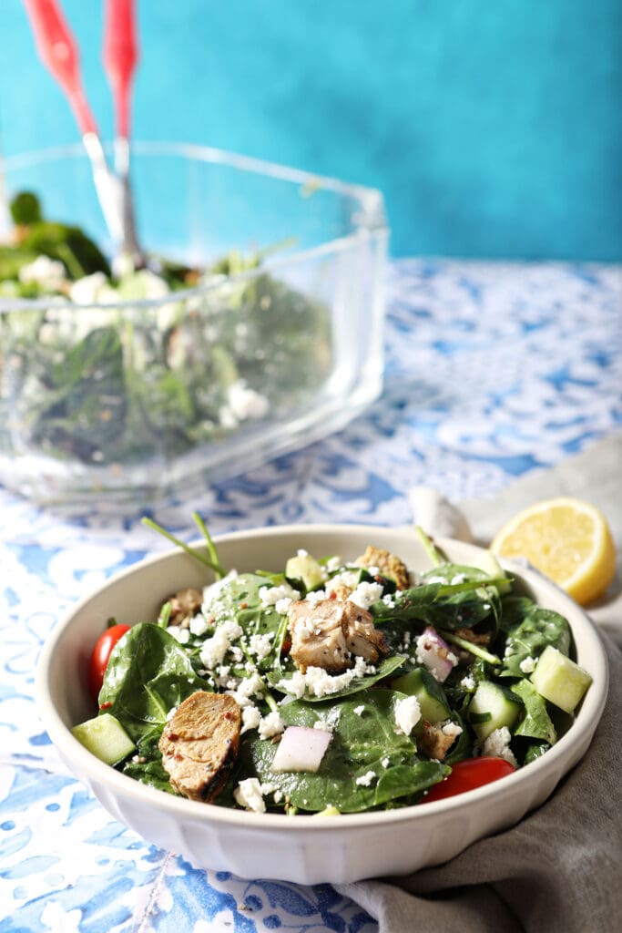 A bowl of chicken shawarma salad on a blue and white tiled surface