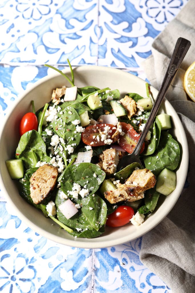 Overhead of a large bowl of shawarma chicken salad on a blue and white tiled surface