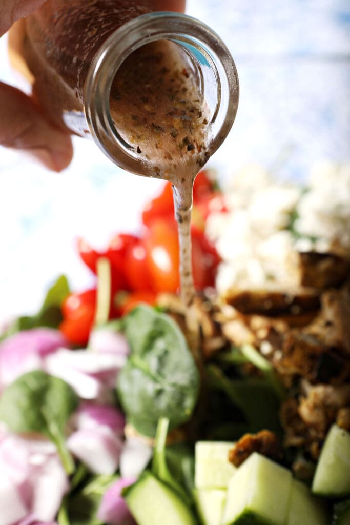 Red wine vinaigrette drizzles on top of a spinach salad