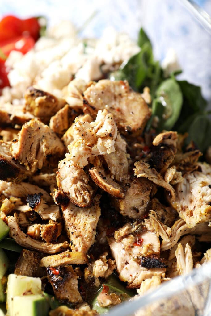 Close up of chicken shawarma in a bowl of salad before tossing