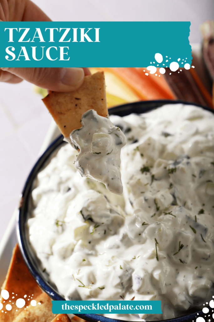 A homemade pita chip dips into a bowl of chunky tzatziki sauce with the text Tzatziki Sauce