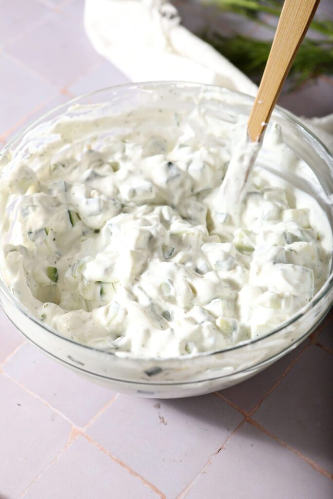 Tzatziki sauce in a large bowl with a rubber spatula after stirring