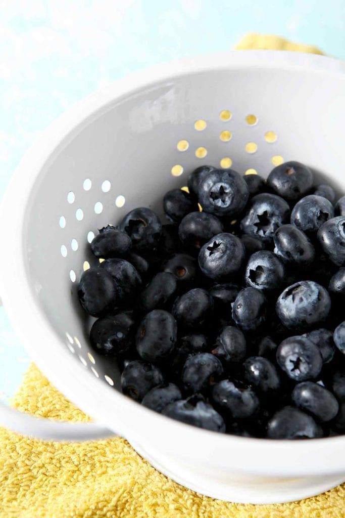 Fresh blueberries, in a white colander, on a yellow towel