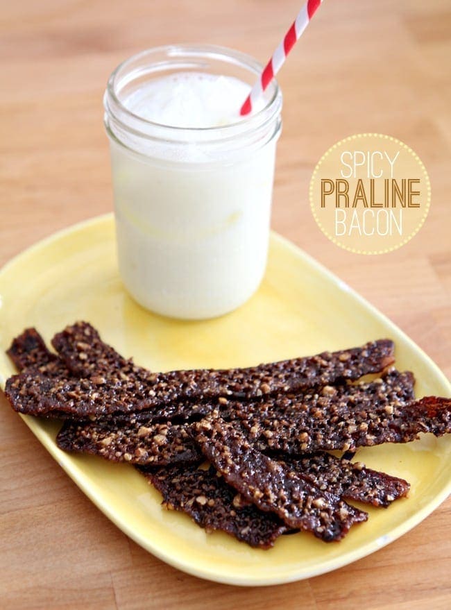 A stack of Praline Candied Bacon sits on a yellow plate on a wooden surface with a glass of milk