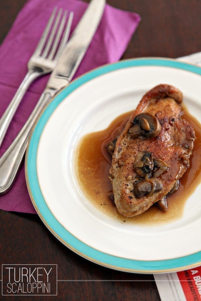 A white plate with a turquoise border holds a serving of Turkey Scaloppini with juices