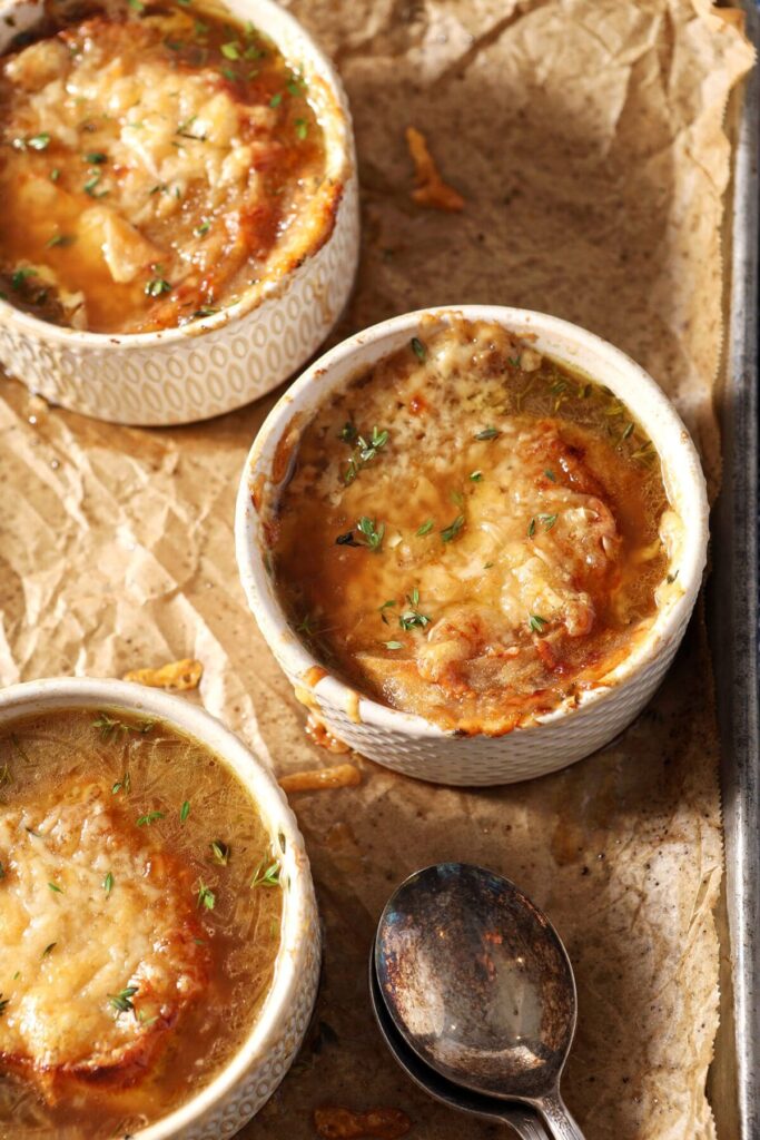 Three bowls of French Onion Soup straight out of the broiler with crusty cheese and bread on top