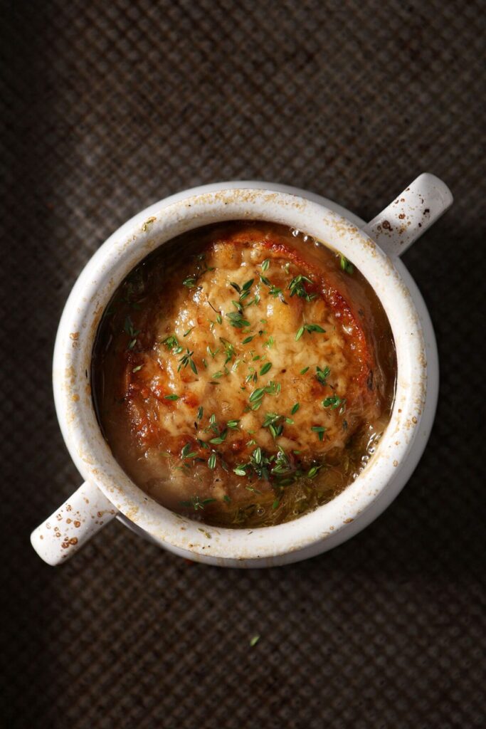 Close up of a bowl of French Onion Soup on a sheet pan after coming out of the broiler