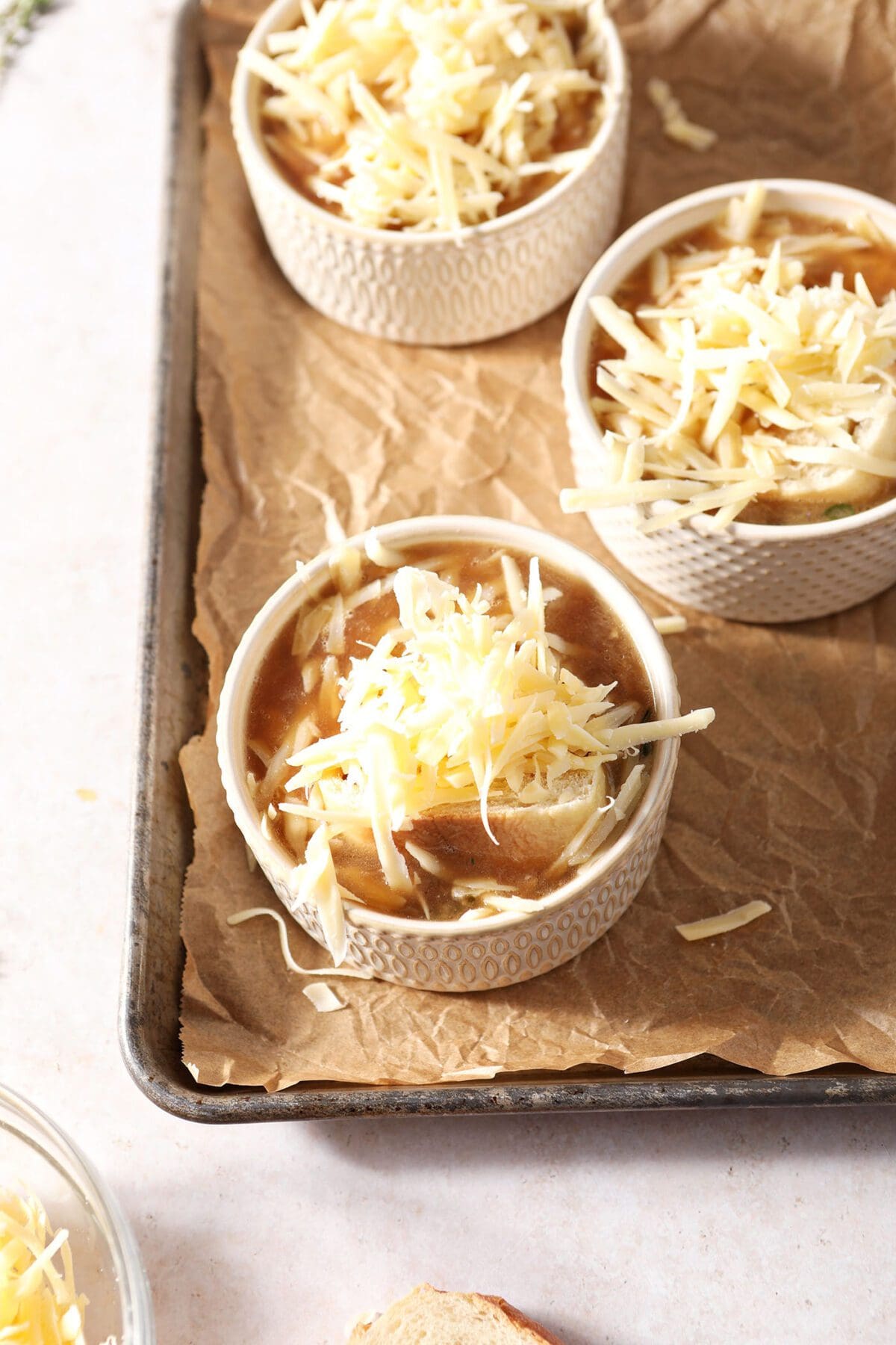 Three bowls of French onion soup topped with fresh bread slices and gruyere cheese