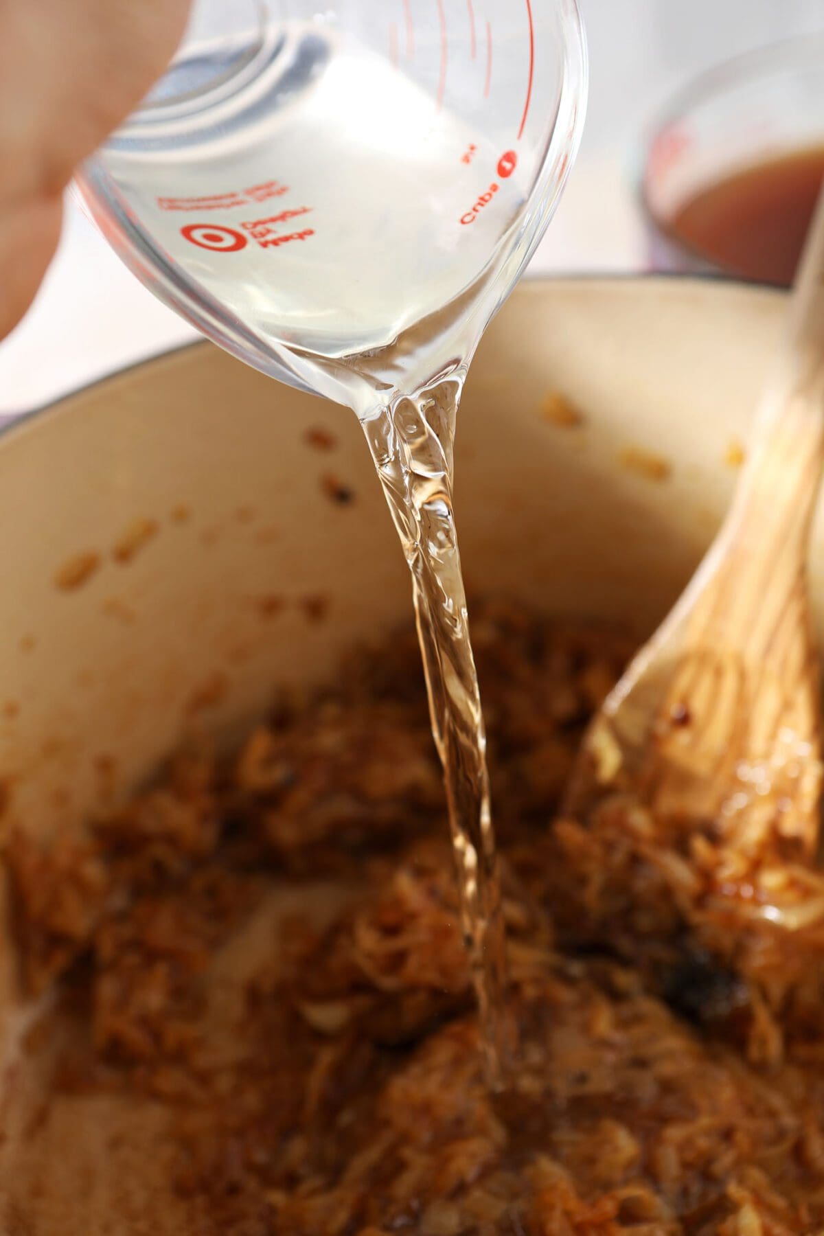 White wine pours on top of caramelized onions