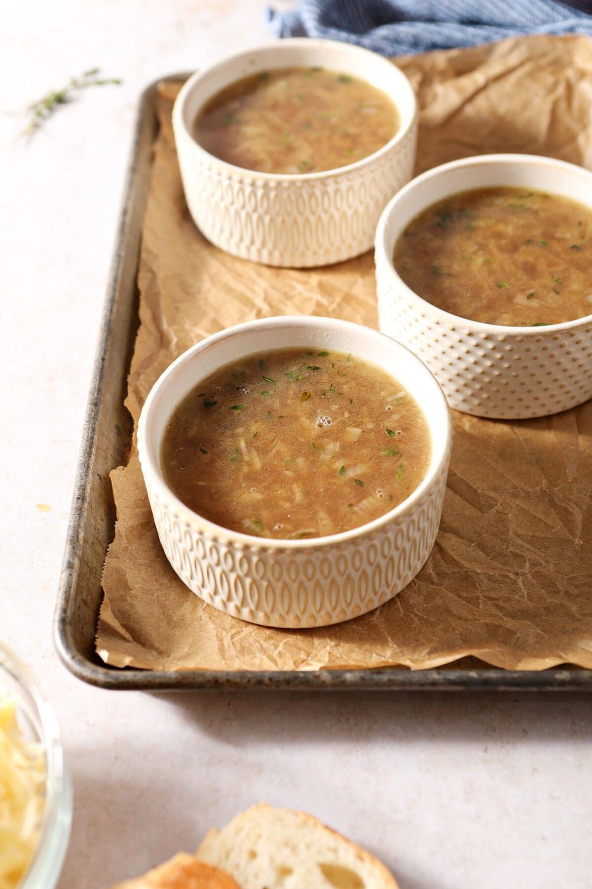 Three containers of French onion soup before broiling