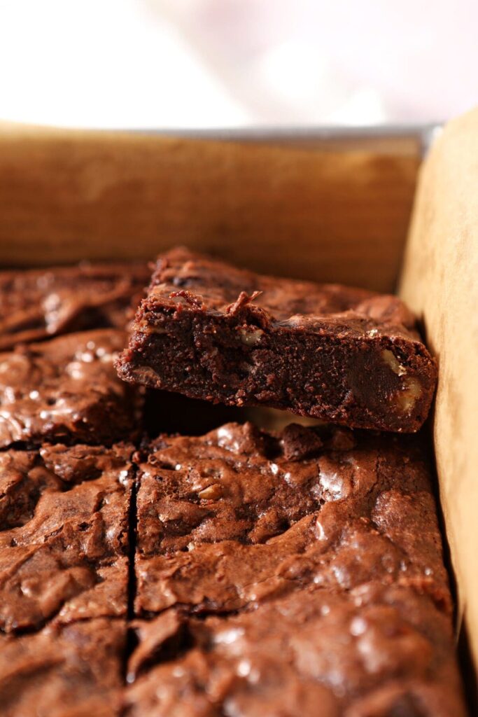 A sliced brownie leans against others in a pan after slicing