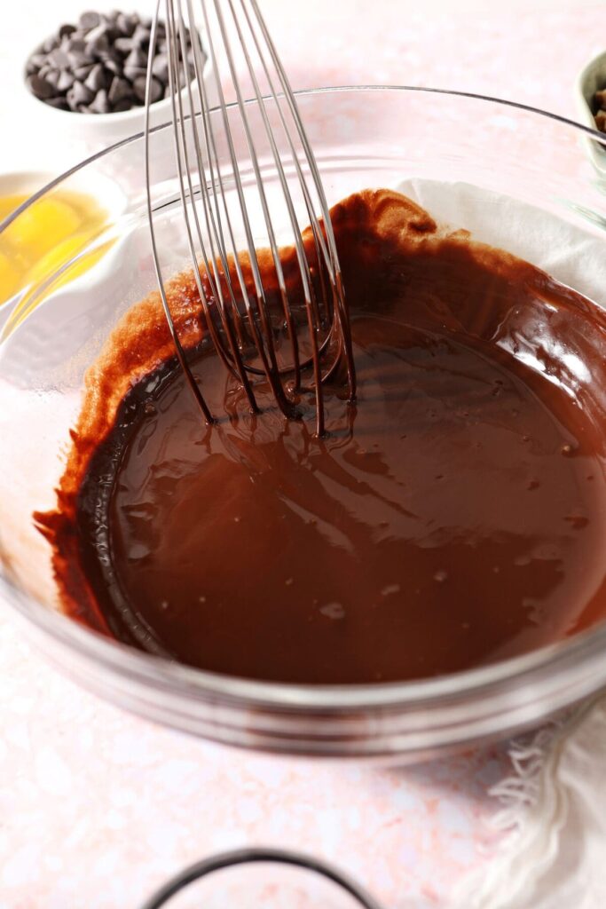 A whisk in a bowl with melted brownie ingredients