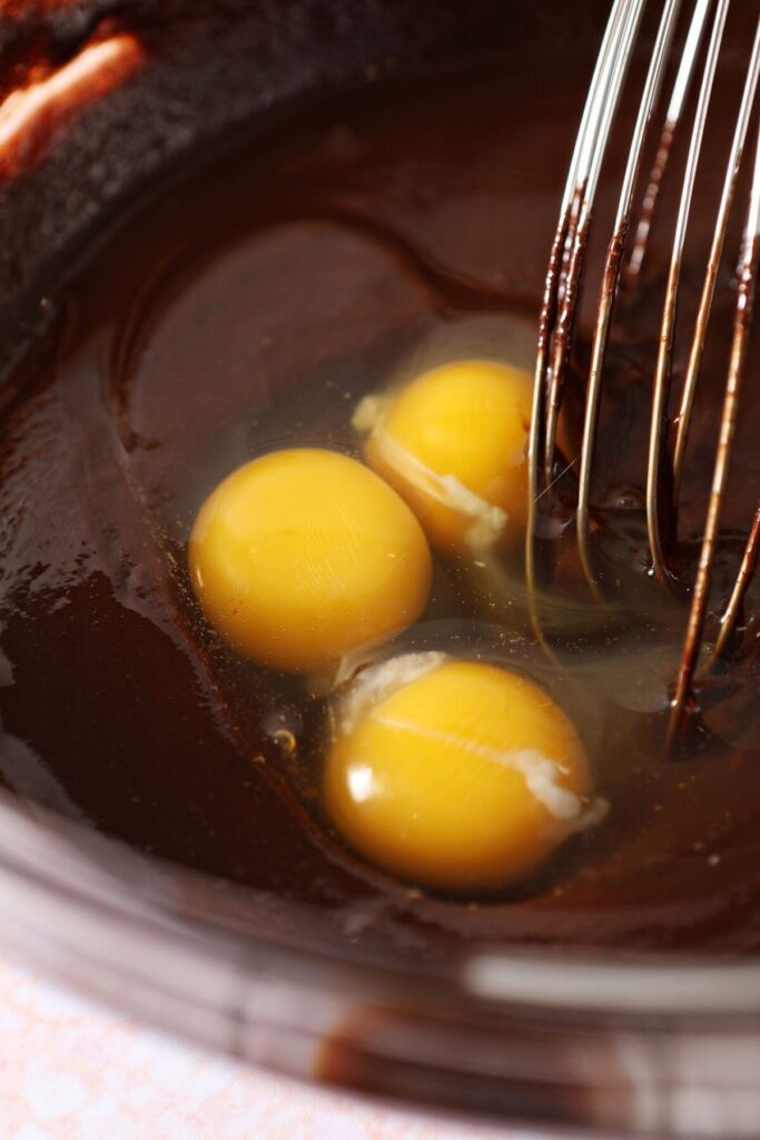 Eggs in a bowl with a chocolate mixture and a whisk