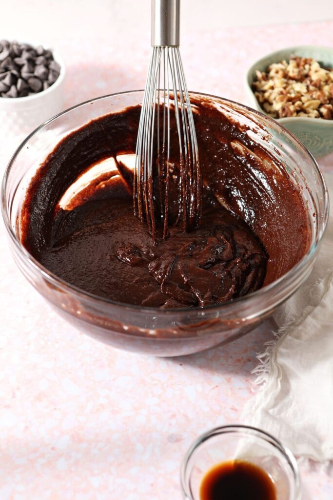 A whisk sits in a bowl with a chocolate mixture