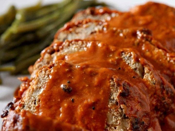 Close up of sliced Slow Cooker Turkey Meatloaf, smothered in tomato sauce, before serving