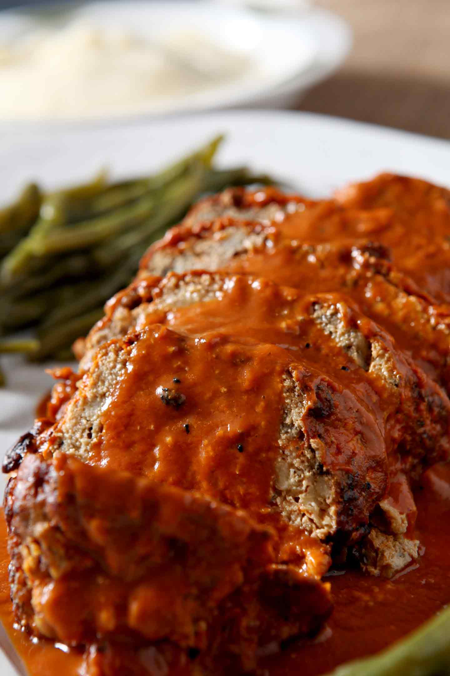 Close up of sliced Slow Cooker Turkey Meatloaf, smothered in tomato sauce, before serving