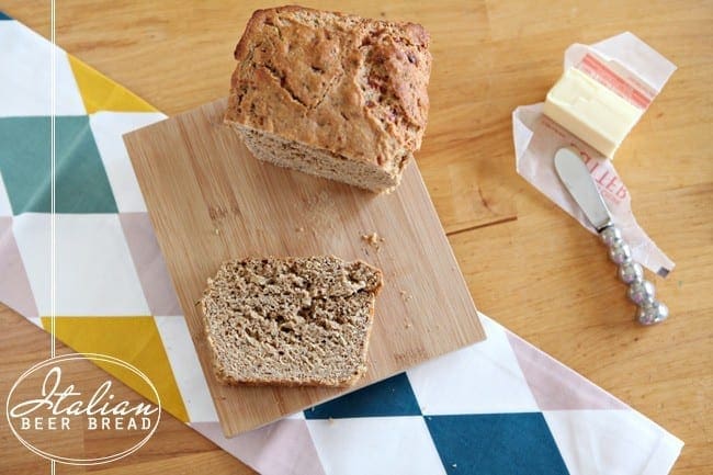 A slice of bread on wood cutting board next to stick of butter