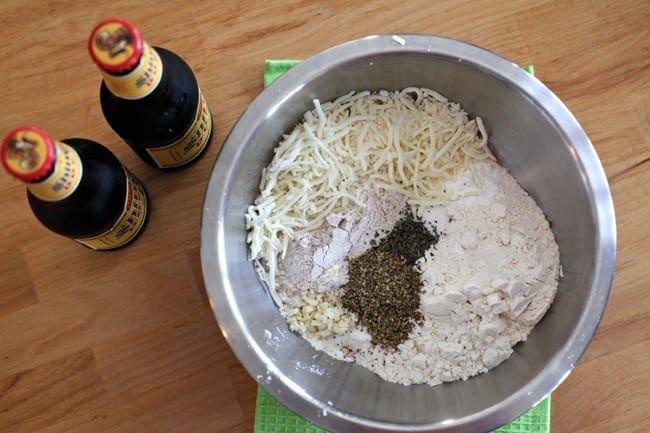 Overhead view of ingredients in a bowl next to two bottles of beer 