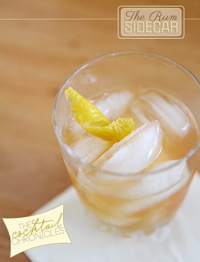 A close up of a cocktail glass holding a golden drink with a lemon twist