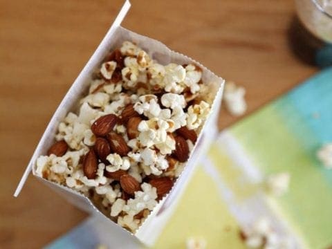 Caramel Corn with Almonds in a white bag on top of linens