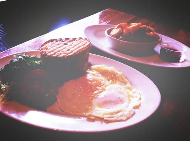 Fried eggs, a salad and two slices of toasted bread on a white plate